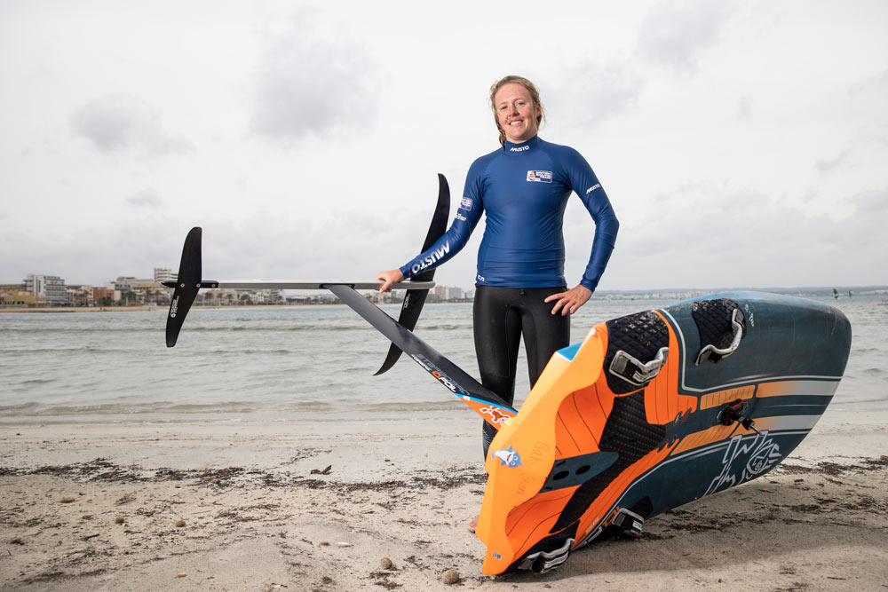 Emma wilson posing on the sandy shore with her wind foil